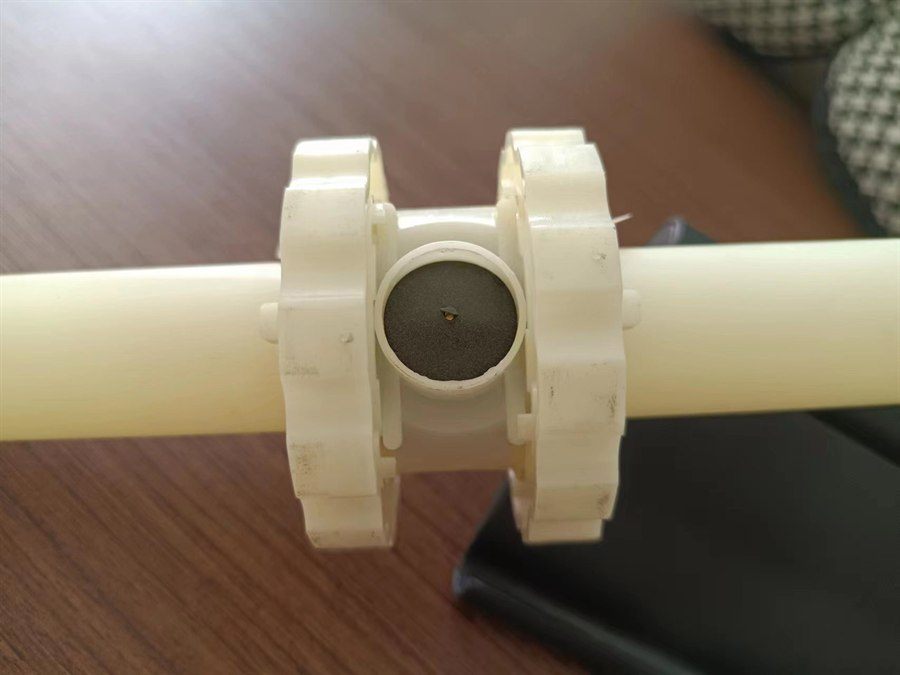 Close-up of the black membrane disc showing the single orifice at its centre
