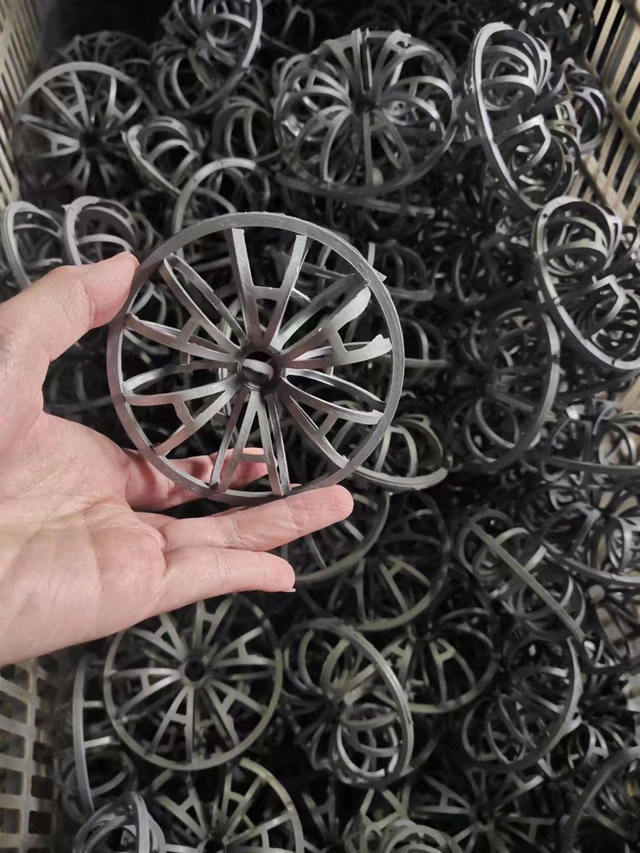 Hand holding a rosette ring in front of a bin of bulk-packed rings